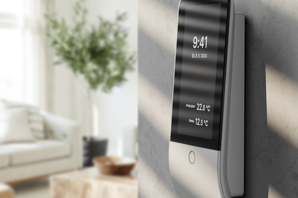 Modernes Smart-Home-Gerät zur Temperatur- und Zeitüberwachung an der Wand in einem hellen Wohnzimmer. Zeigt aktuelle Uhrzeit und Raumtemperaturen.