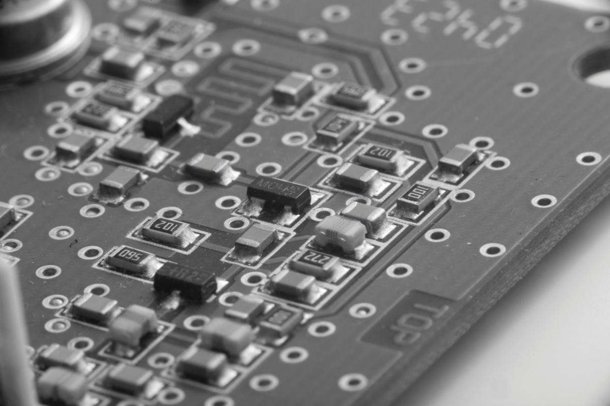 Makroaufnahme einer elektronischen Leiterplatte mit sichtbaren SMD-Bauteilen, Lötstellen und Leiterbahnen.