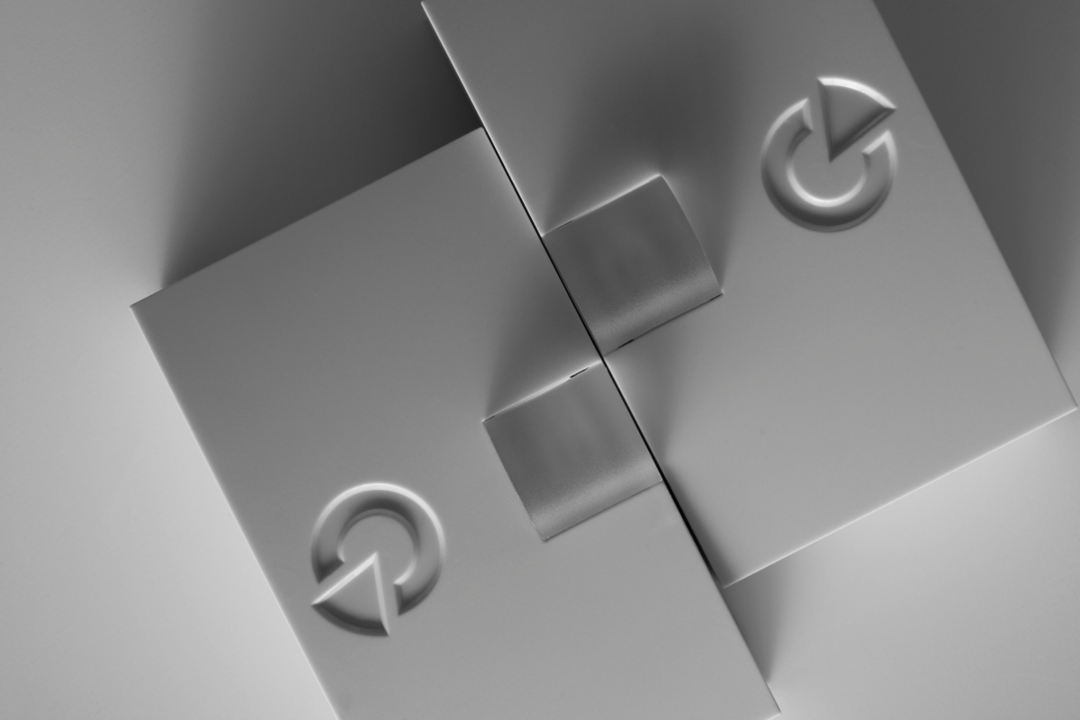 Nahaufnahme von zwei Metallteilen, die durch eine Scharnierverbindung verbunden sind, mit einem eingebauten Schaltknopf und einer klaren, glatten Oberfläche.